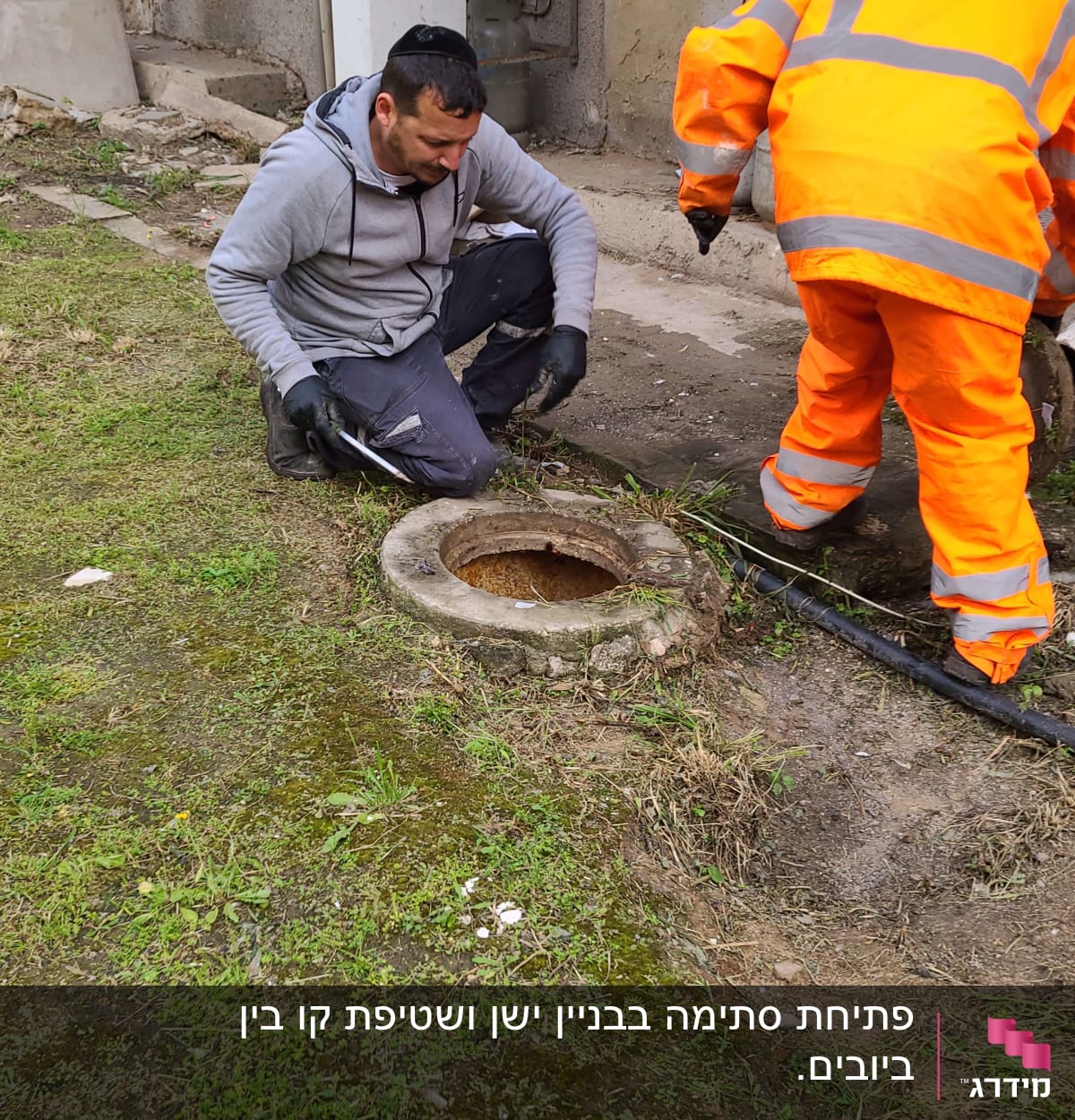 שני אנשים עובדים ליד פתח ביוב עם צינור